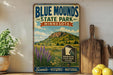 A vintage-style sign for Blue Mounds State Park in Minnesota, featuring a scenic landscape with mountains, grass, and wildflowers.