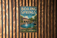 A vintage metal sign for Boiling Springs State Park in Oklahoma, featuring a scenic illustration of a pond with a waterfall and a bridge.