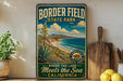 A vintage-style metal sign for Border Field State Park, featuring a scenic landscape with mountains, a desert, and a coastline.
