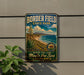 A vintage-style metal sign for Border Field State Park, featuring a scenic landscape with mountains, a beach, and a desert.