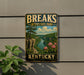 A vintage-style sign for Breaks Interstate Park in Kentucky, featuring a scenic landscape with a river, mountains, and pink flowers.