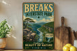 A vintage-style poster advertising Breaks Interstate Park, featuring a scenic mountain landscape with a winding river and lush greenery.