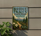 A vintage metal sign for Bridle Trails State Park in Washington, featuring a scenic mountain landscape with a trail and flowers.