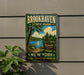 A vintage-style metal sign for Brookhaven State Park, featuring a scenic landscape with a lake, trees, and a sign indicating the park's name.