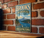 A vintage metal sign for Brooks Memorial State Park in Washington, featuring a scenic mountain landscape and a river.