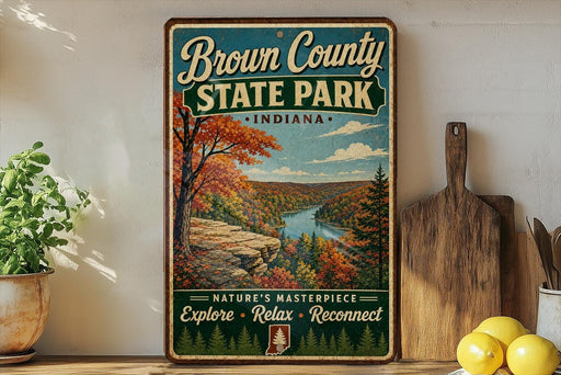 A vintage-style sign for Brown County State Park in Indiana, featuring a scenic landscape with a river and autumn foliage.
