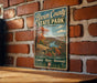 A vintage-style metal sign for Brown County State Park in Indiana, featuring a scenic landscape with a river and autumn foliage.