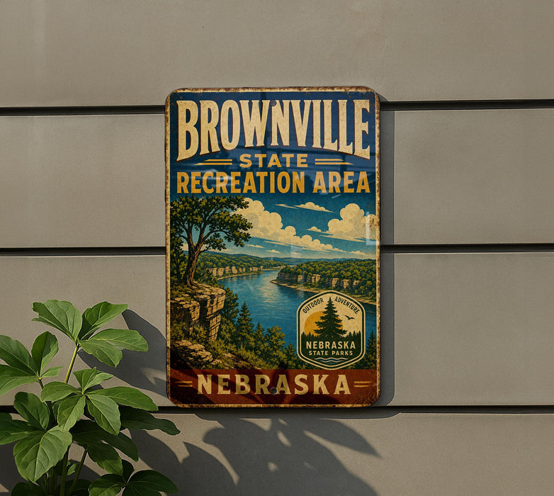 A vintage-style metal sign for the Brownville State Recreation Area in Nebraska, featuring a scenic landscape with a river and mountains.
