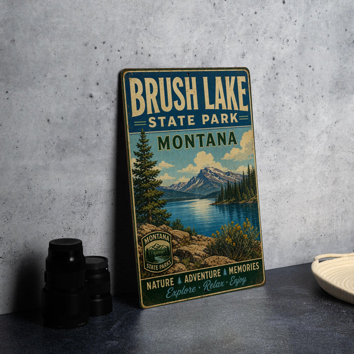 A vintage metal sign for Brush Lake State Park in Montana, featuring a scenic landscape with mountains, trees, and a lake.