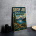 A vintage metal sign for Brush Lake State Park in Montana, featuring a scenic landscape with mountains, trees, and a lake.