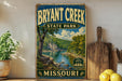 A vintage-style sign for Bryant Creek State Park in Missouri, featuring a scenic landscape with a river and trees.