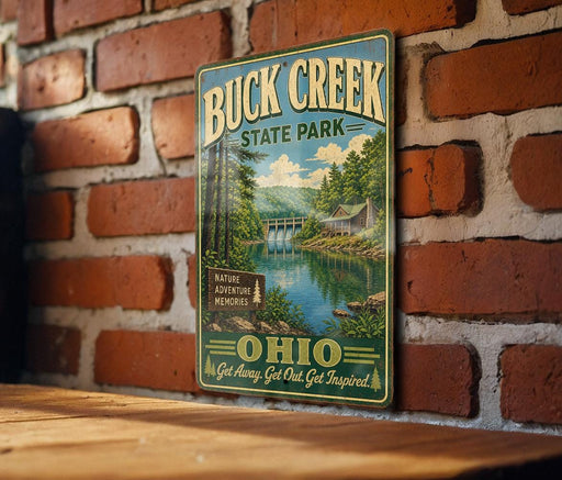 A vintage-style metal sign for Buck Creek State Park in Ohio, featuring a scenic illustration of the park's natural surroundings and a waterfall.