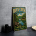 A vintage metal sign for Buck Creek State Park, featuring a scenic landscape with a lake, forest, and bridge.