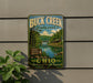 A vintage-style metal sign for Buck Creek State Park in Ohio, featuring a scenic landscape with a lake, forest, and bridge.