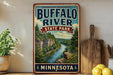 A vintage-style sign for Buffalo River State Park in Minnesota, featuring a scenic illustration of the river surrounded by lush greenery and rocky cliffs.
