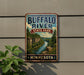 A vintage-style sign for Buffalo River State Park in Minnesota, featuring a scenic illustration of the river surrounded by lush greenery and rocky cliffs.