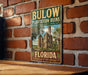 A vintage-style metal sign for Bulow Plantation Ruins, a historic state park in Florida, is displayed on a brick wall.