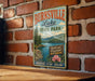 A vintage-style metal sign for Burnville Lake State Park, featuring a scenic illustration of the lake surrounded by mountains and pine trees.