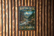 A vintage metal sign for Burton Creek State Park in California, featuring a scenic landscape with a river, mountains, and trees.