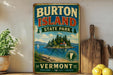 A vintage-style sign for Burton Island State Park in Vermont, featuring a scenic illustration of a lake, island, and mountains.