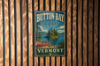 A vintage-style metal sign for Button Bay State Park in Vermont, featuring a scenic image of a lake and a red canoe.