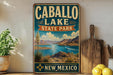 A vintage-style sign for Caballo Lake State Park in New Mexico, featuring a scenic landscape with mountains, a lake, and a desert backdrop.