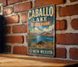 A vintage metal sign for Caballo Lake State Park in New Mexico, featuring a scenic illustration of the lake and mountains.