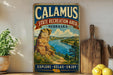 A vintage-style sign for Calamus State Recreation Area in Nebraska, featuring a scenic landscape with a river and mountains.