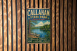 A vintage metal sign for Callahan State Park in Massachusetts, featuring a scenic landscape with a lake and pine trees.