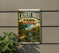 A vintage-style metal sign for Calvert Vaux Park in New York, featuring a scenic landscape with a bridge and trees.
