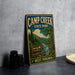A vintage-style sign for Camp Creek State Park in West Virginia, featuring a scenic illustration of a forest and a river.
