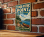 A vintage-style metal sign for Canoe-Picnic Point State Park in New York, featuring a scenic image of a canoe on a lake surrounded by trees and mountains.