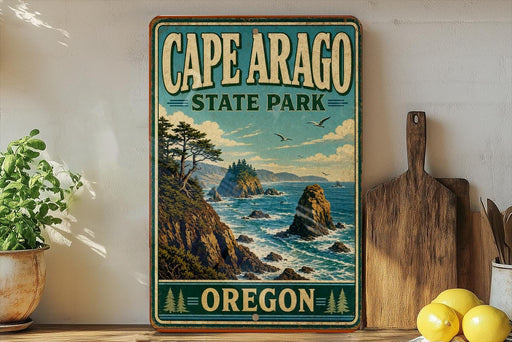 A vintage-style sign for Cape Arago State Park in Oregon, featuring a scenic coastal landscape with rocky cliffs, trees, and the ocean.