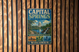 A vintage metal sign for the Capital Springs State Recreation Area in Wisconsin, featuring a scenic illustration of the state's natural beauty.