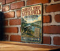 A vintage-style metal sign for Carniff Ferry Battlefield, a State Park in West Virginia, featuring a cannon and a monument.