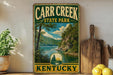 A vintage-style sign for Carr Creek State Park in Kentucky, featuring a scenic landscape with a lake and mountains.