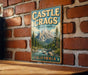 A vintage-style metal sign for Castle Crags State Park in California, featuring a mountain landscape and a river.