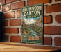 A vintage-style metal sign for Castlewood Canyon State Park, featuring a scenic illustration of the canyon landscape.