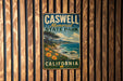 A vintage metal sign for Caswell Memorial State Park in California, featuring a scenic landscape with a beach, mountains, and trees.