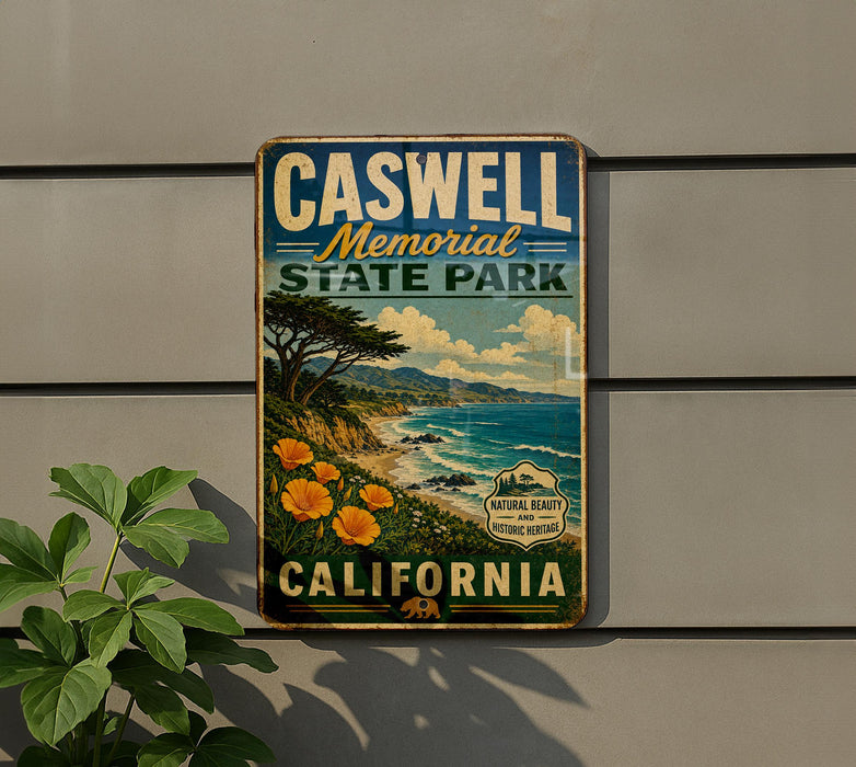 A vintage metal sign for Caswell Memorial State Park in California, featuring a scenic landscape with a coastal cliff, ocean, and trees.
