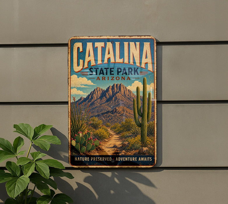 A vintage-style metal sign for Catalina State Park in Arizona, featuring a desert landscape with mountains, cacti, and a path leading to the park.