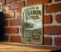 A vintage-style metal sign for Cedar's of Lebanon State Park in Tennessee, featuring a scenic landscape with a tree and a lake.