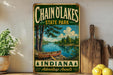 A vintage-style metal sign for Chain of Lakes State Park in Indiana, featuring a scenic image of a lake and a canoe.