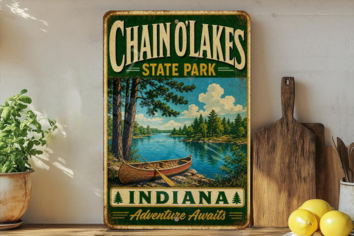 A vintage-style metal sign for Chain of Lakes State Park in Indiana, featuring a scenic image of a lake and a canoe.