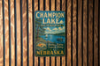 A vintage metal sign for Champion Lake, a state recreation area, is displayed on a wooden wall.