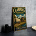 A vintage metal sign for Champoeg, Oregon, featuring an illustration of a covered wagon and a building, with the text "Champoeg State Heritage Area Oregon" and "Where Oregon Began" on it.