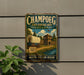 A vintage metal sign for Champoeg State Heritage Area in Oregon, featuring a wagon and a wooden building in a scenic landscape.