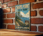 A vintage metal sign for Chapel Point State Park in Maryland, featuring a scenic image of the park and the Chesapeake Bay.