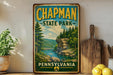 A vintage-style metal sign for Chapman State Park in Pennsylvania, featuring a scenic landscape with a river and forest.