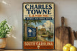 A vintage-style sign for Charles Towne Landing, a historic site in South Carolina, featuring a wooden sign with a palm tree and a ship, along with a wooden paddle and a potted plant.